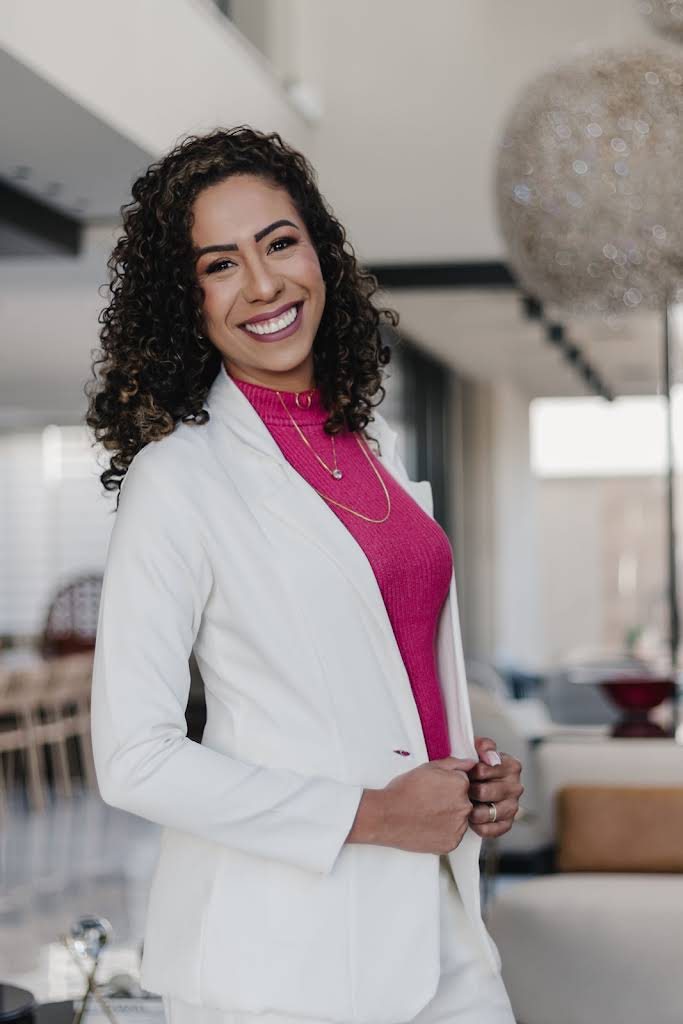 Keri sorrindo, de blazer branco e blusa rosa